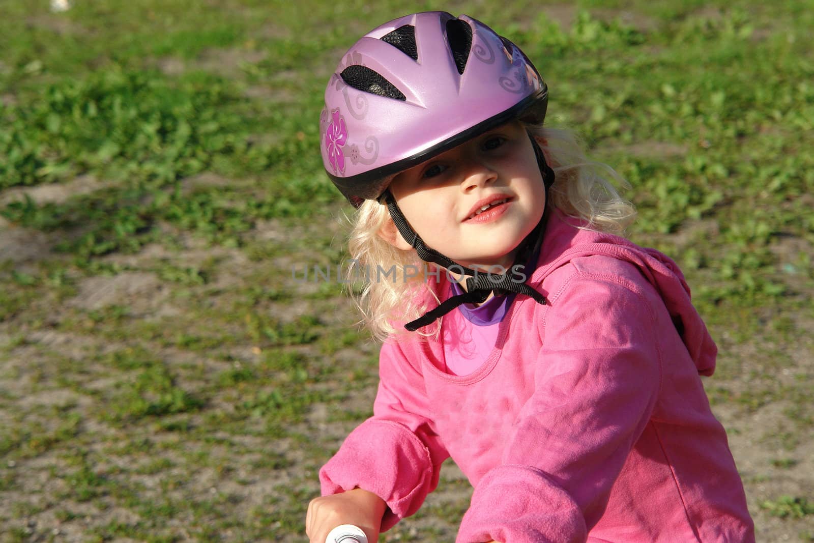 Cute little girl with a helmet riding a bike