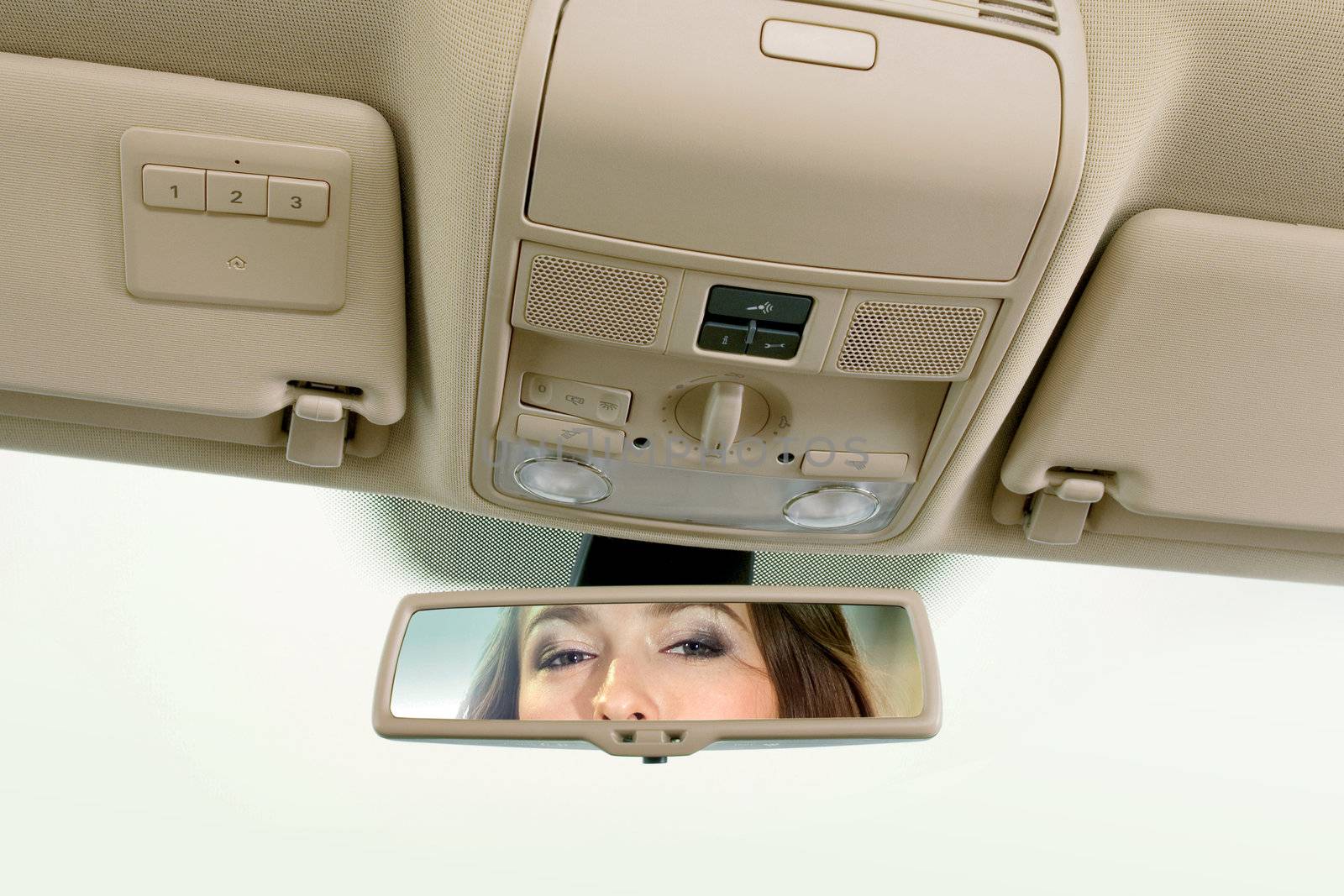 Young woman sits on driver's seat and looks in the rear-view mirror