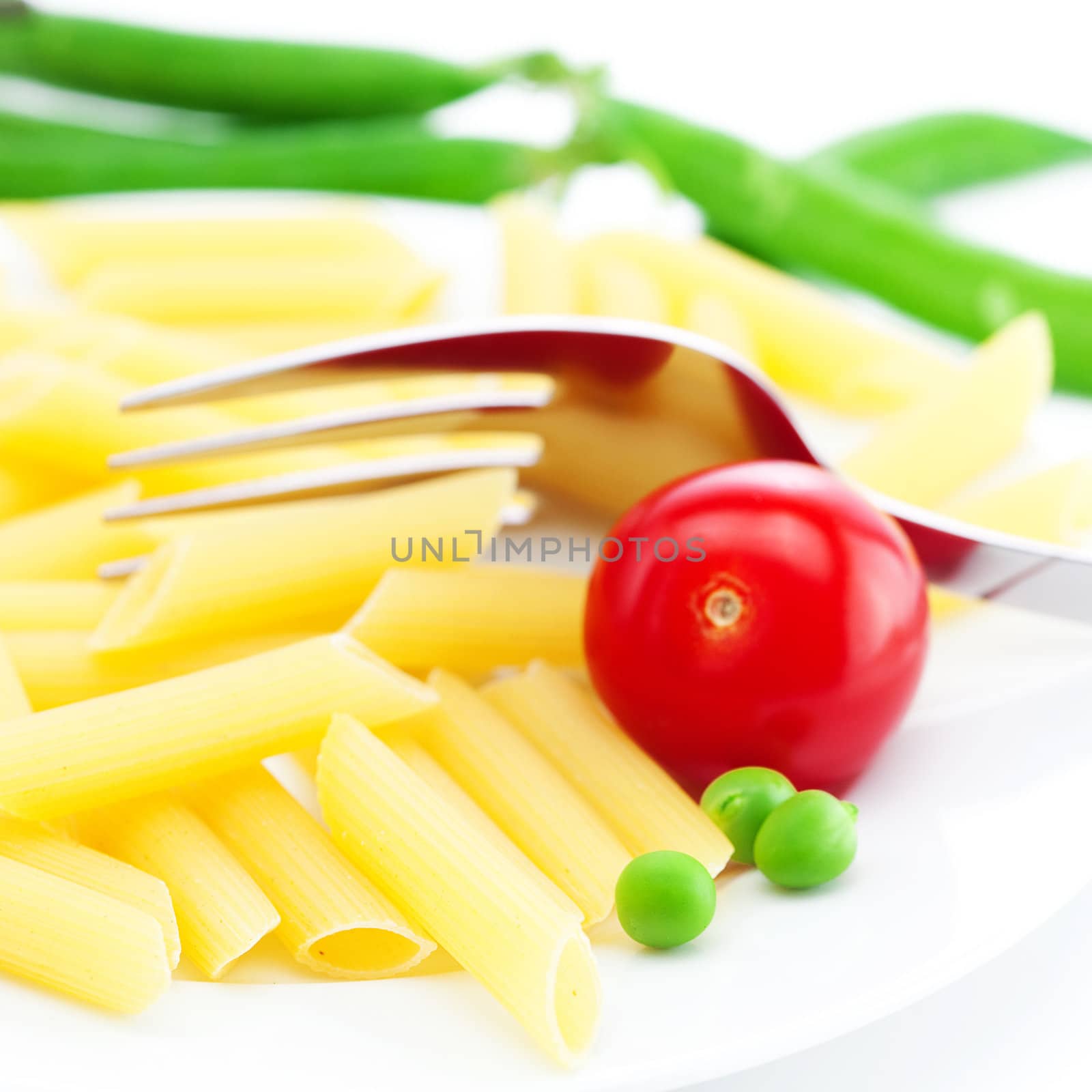 tomatoes, peas, pasta and fork on a plate isolated on white by jannyjus