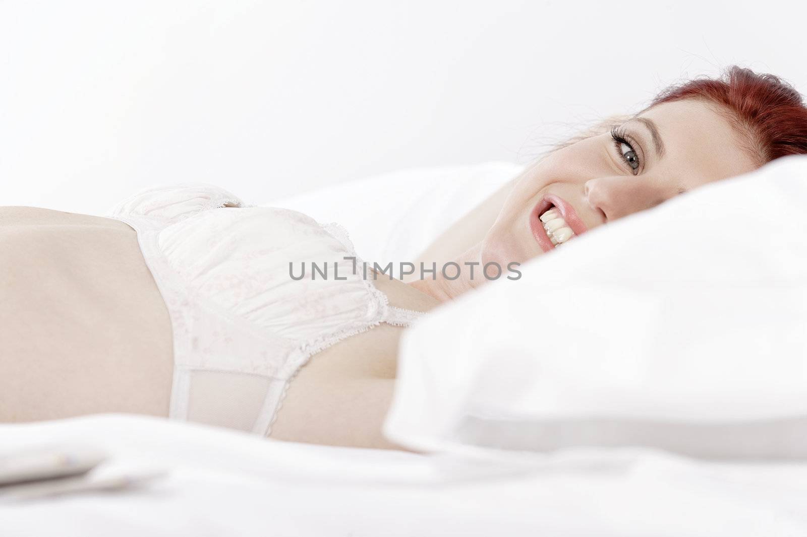 Attractive young woman lying on her bed in her underwear at home