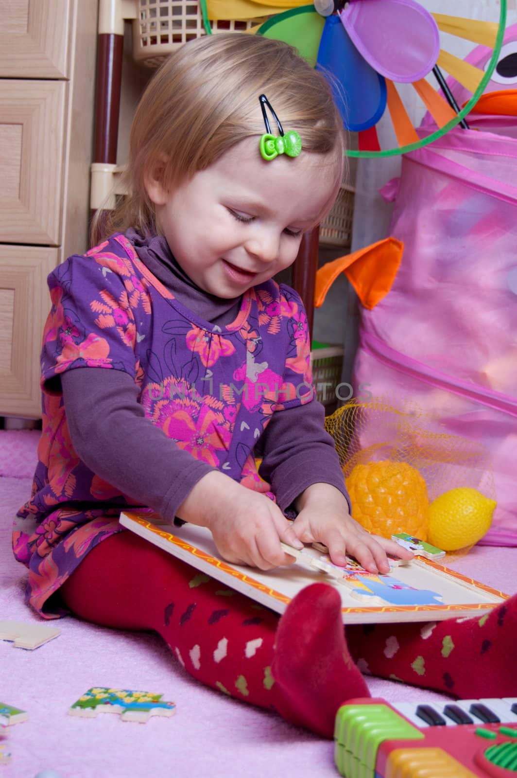 Baby girl collecting puzzle in playing-room