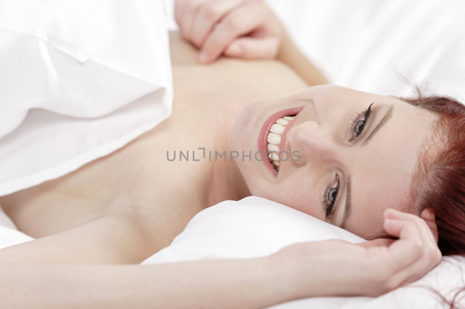 Attractive young woman holding a pillow on her bed at home
