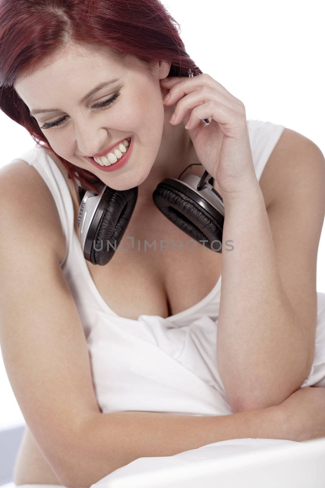 Attractive young woman listening to music at home on her bed