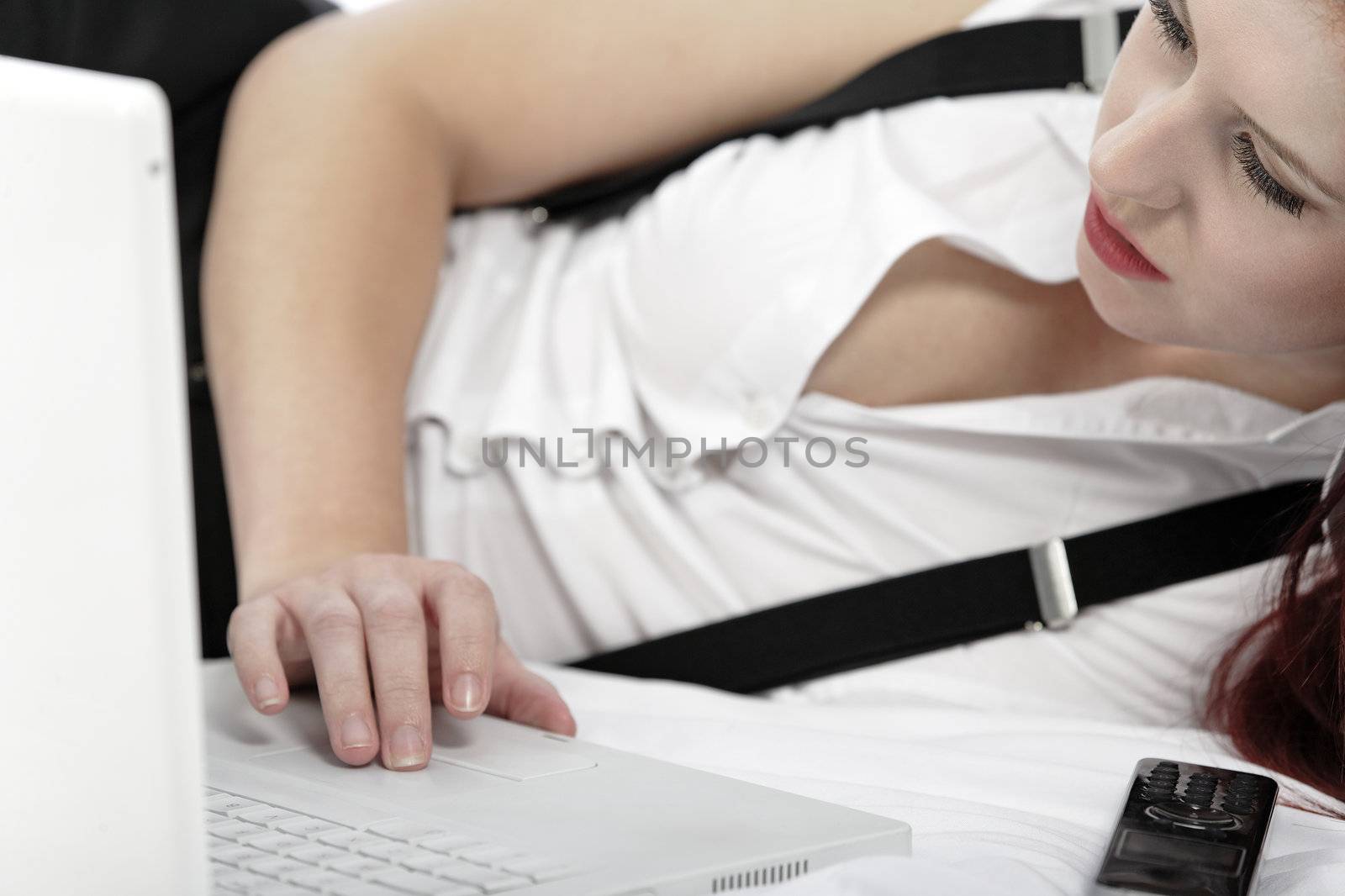 Professional business woman lying on a bed after a long day in the office still working on the laptop computer