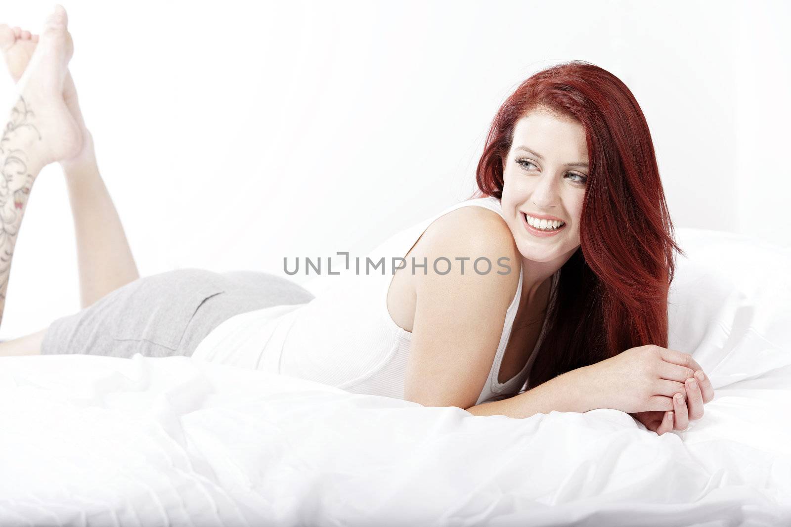 Young woman lying on her white bed at home relaxing