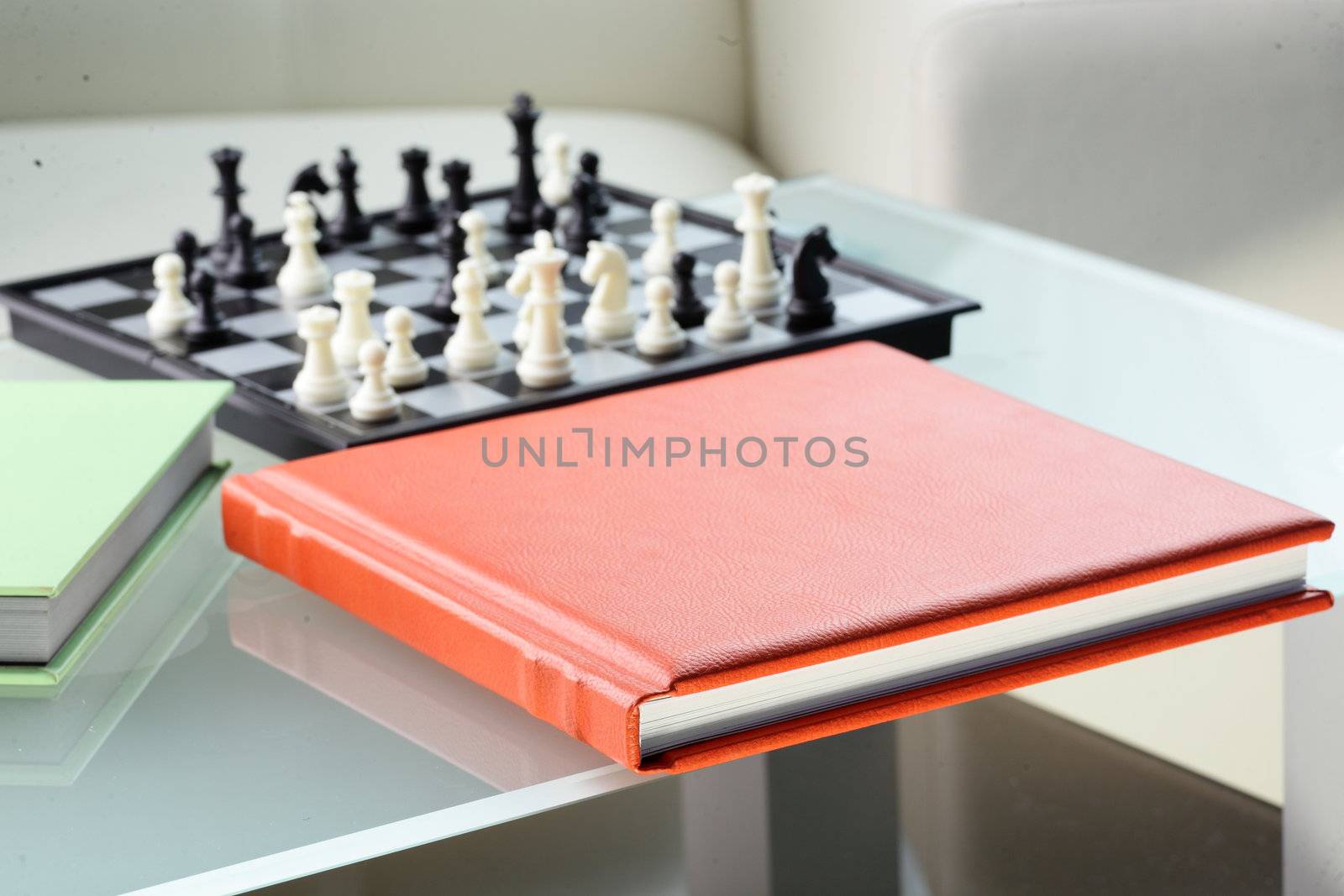 orange leather book on bright background and chess