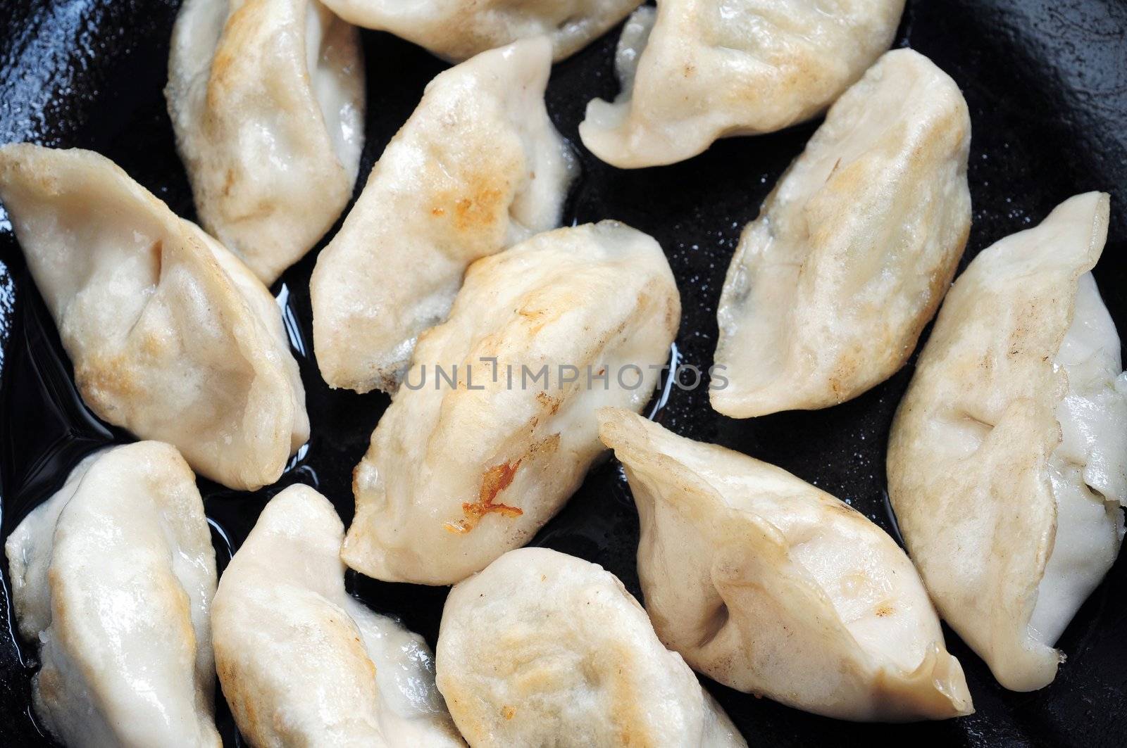 Chinese dumplings being fired in an iron pan