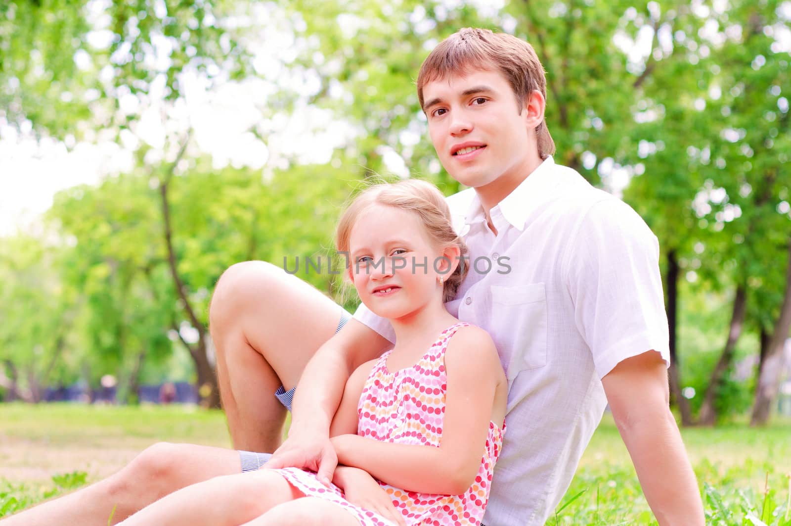 Father and daughter sitting together on the grass, and spend time with family