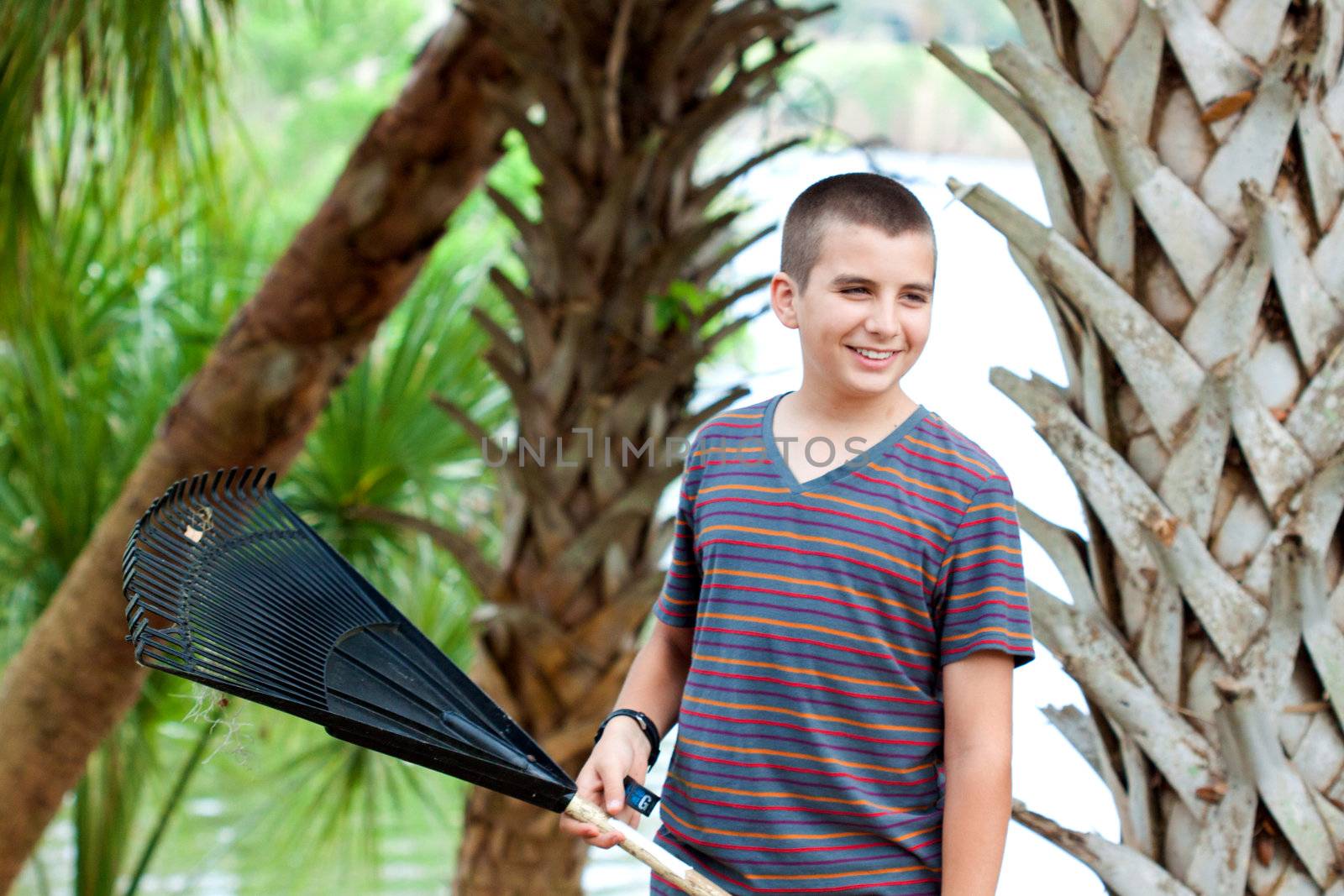 Boy outdoors with a rake smiling and having a good time