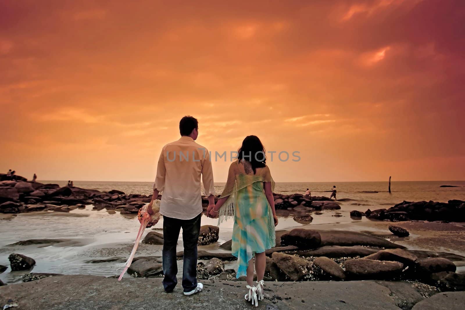 sweet couples by hand in hand on the beach at dusk