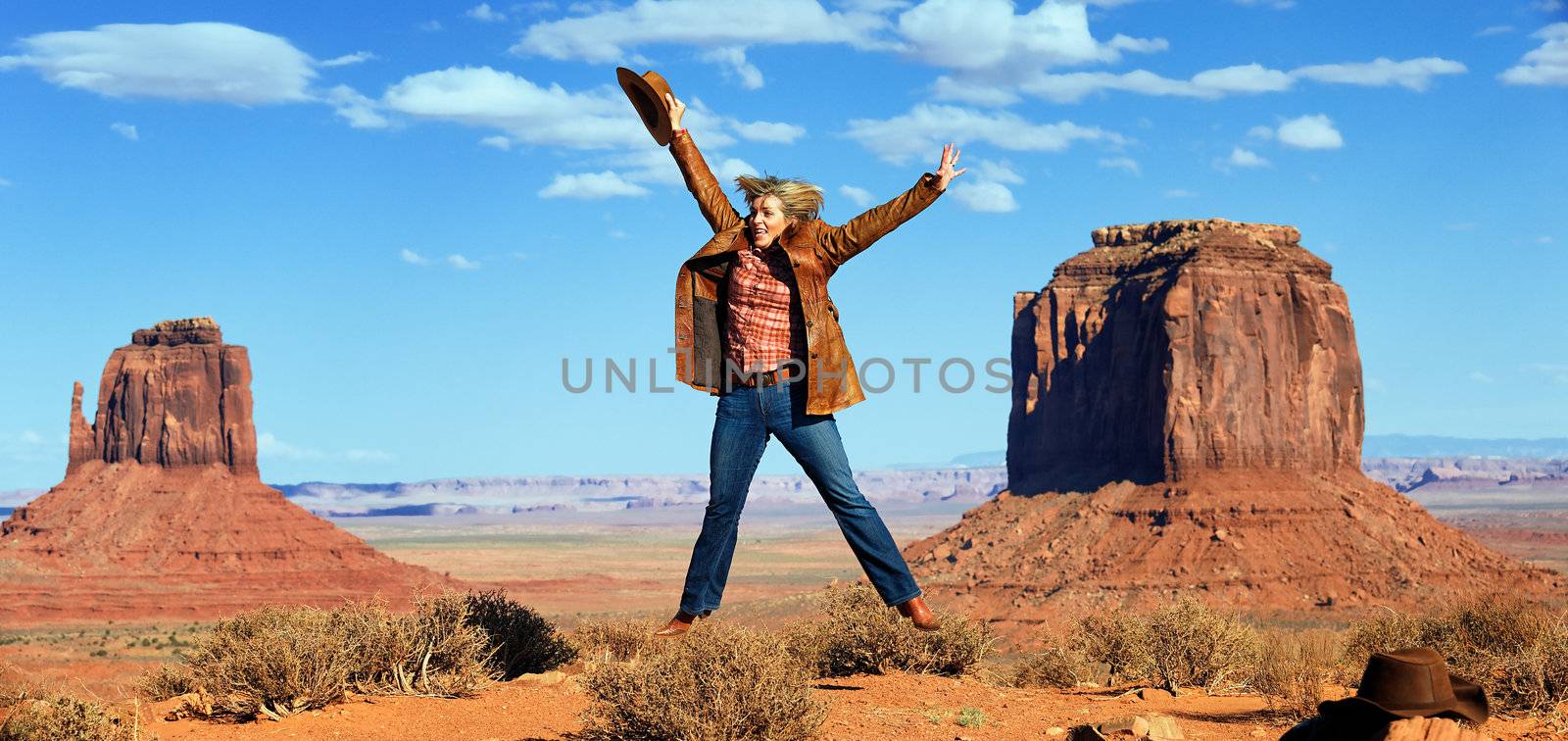 panoramic view of cowgirl jumping at Monument Valley, Utah, USA