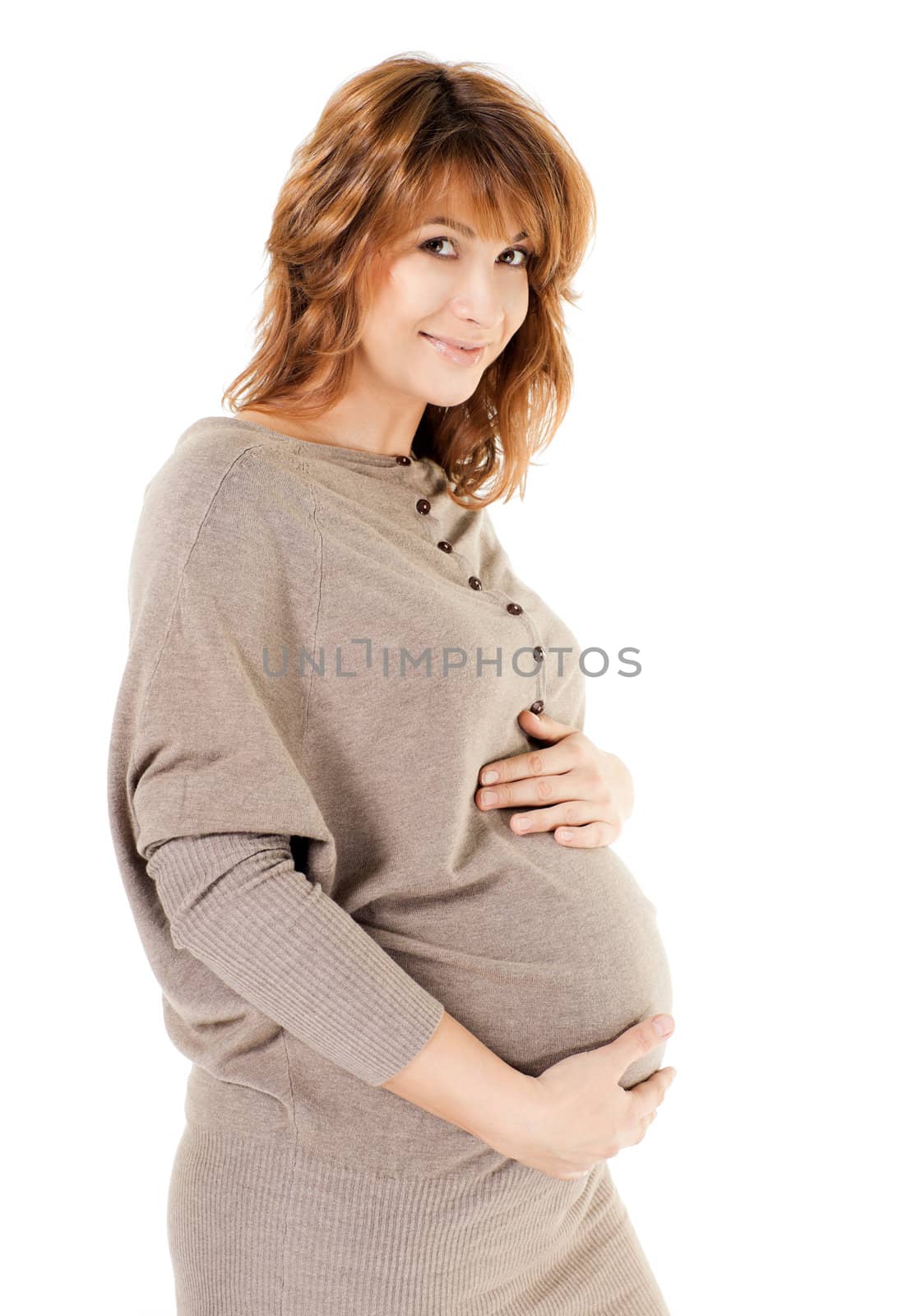 Beautiful pregnant woman holding her belly, smiling at camera