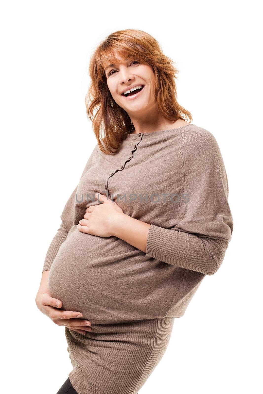 Image of charming pregnant female touching her tummy, laughing and looking positive at camera