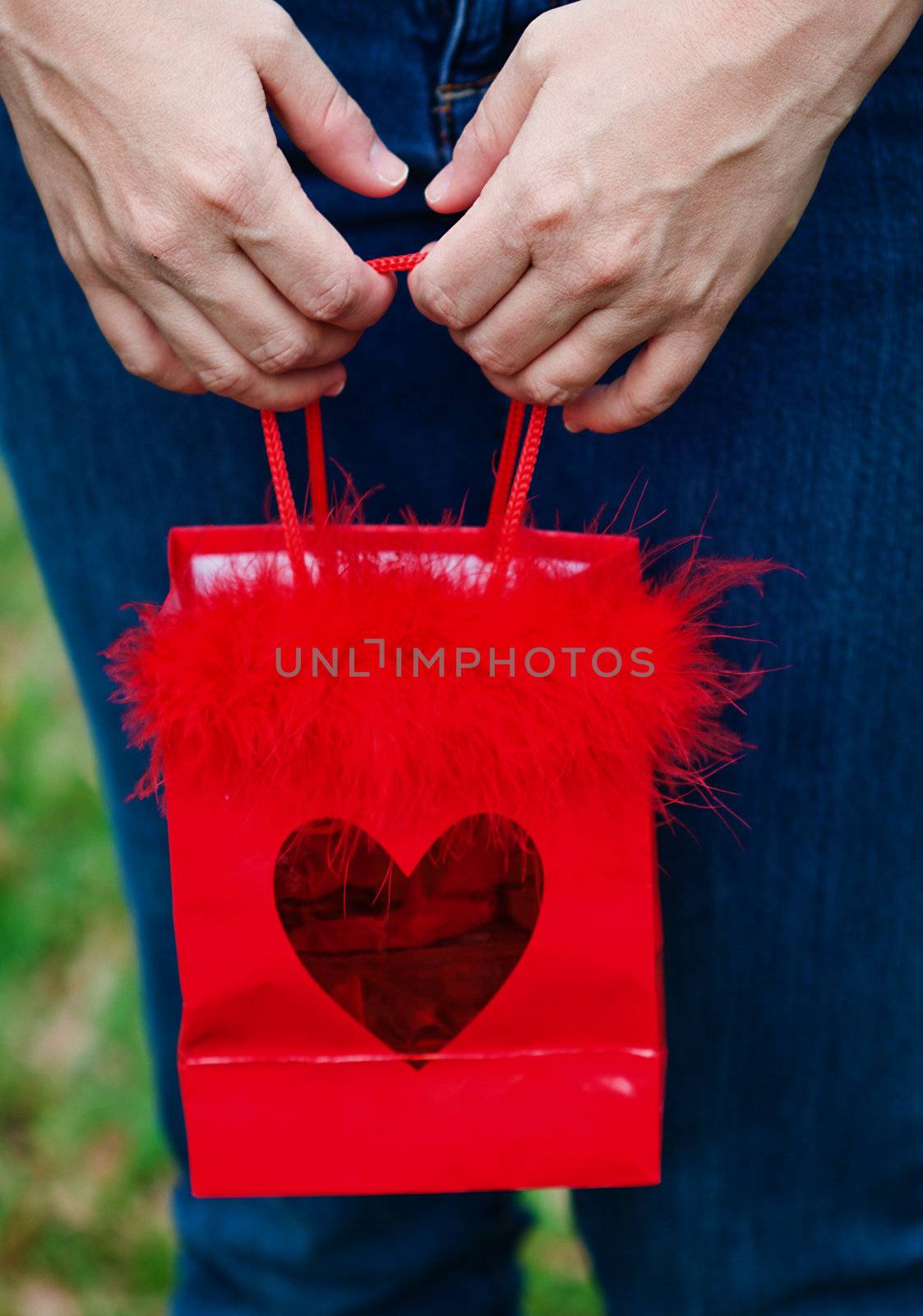 Hands holding red gift bag with heart printed