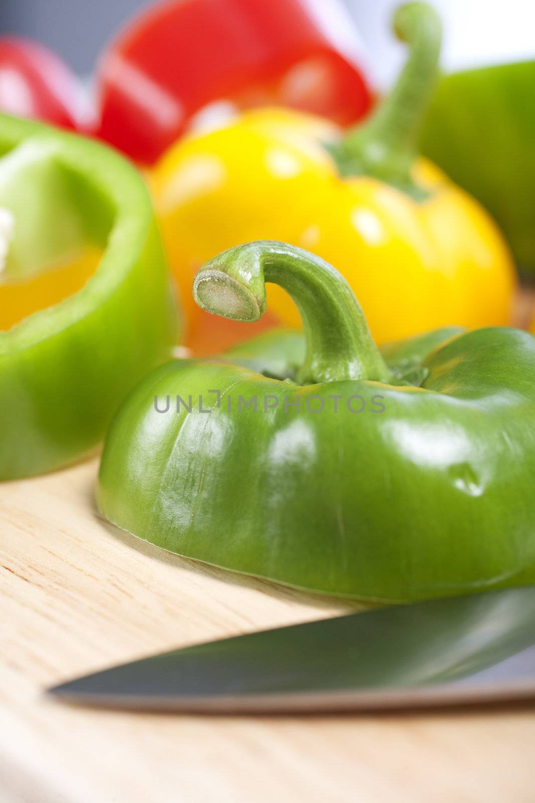 Selection of red green and yellow peppers sliced up on a chopping board