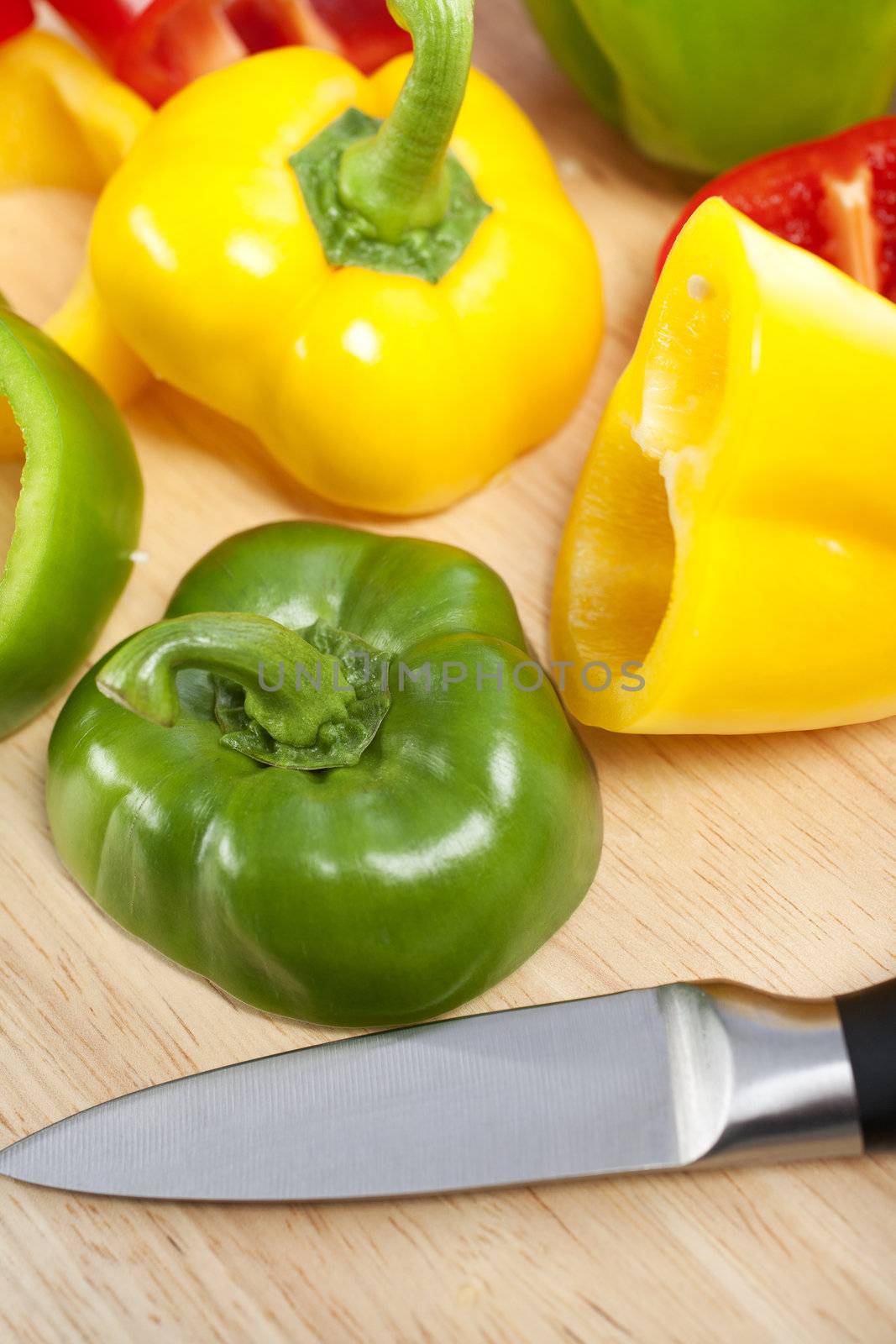 Selection of red green and yellow peppers sliced up on a chopping board