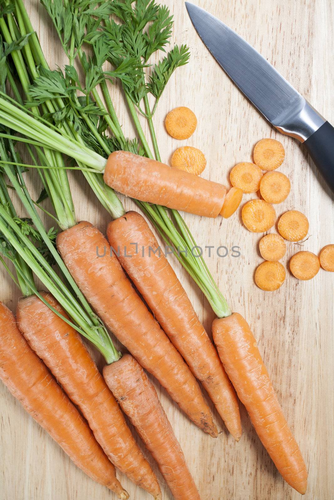 Fresh organic carrots on a wooden chopping board with knife