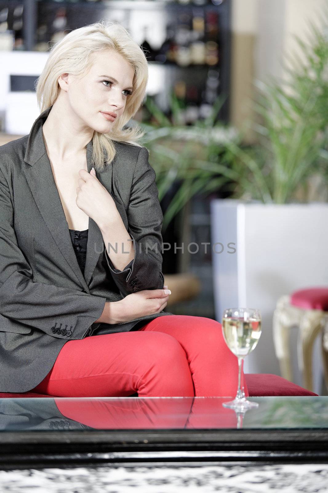 Attractive young woman enjoying a glass of white wine in a wine bar.