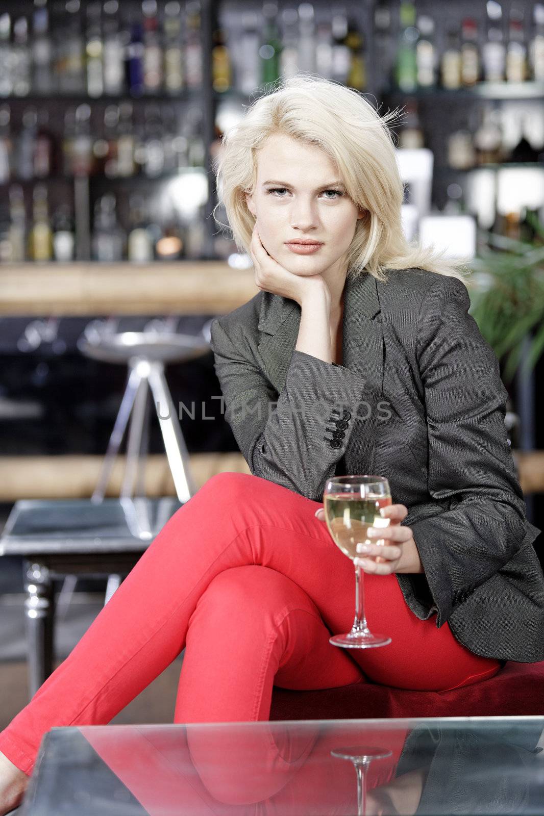 Attractive young woman enjoying a glass of white wine in a wine bar.