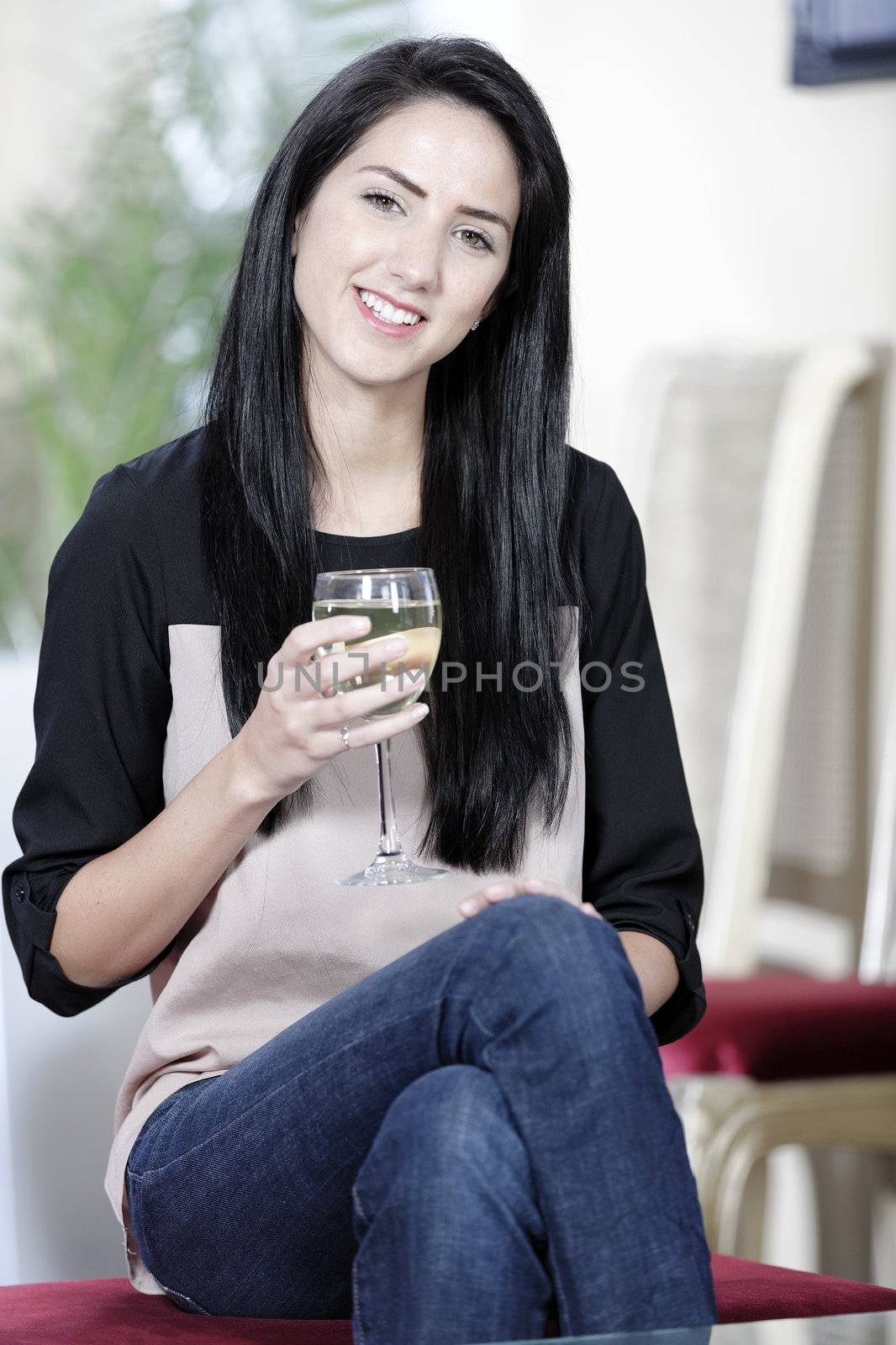 Attractive young woman enjoying a glass of white wine in a wine bar.