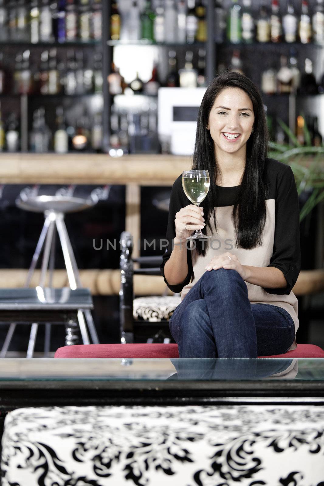 Attractive young woman enjoying a glass of white wine in a wine bar.