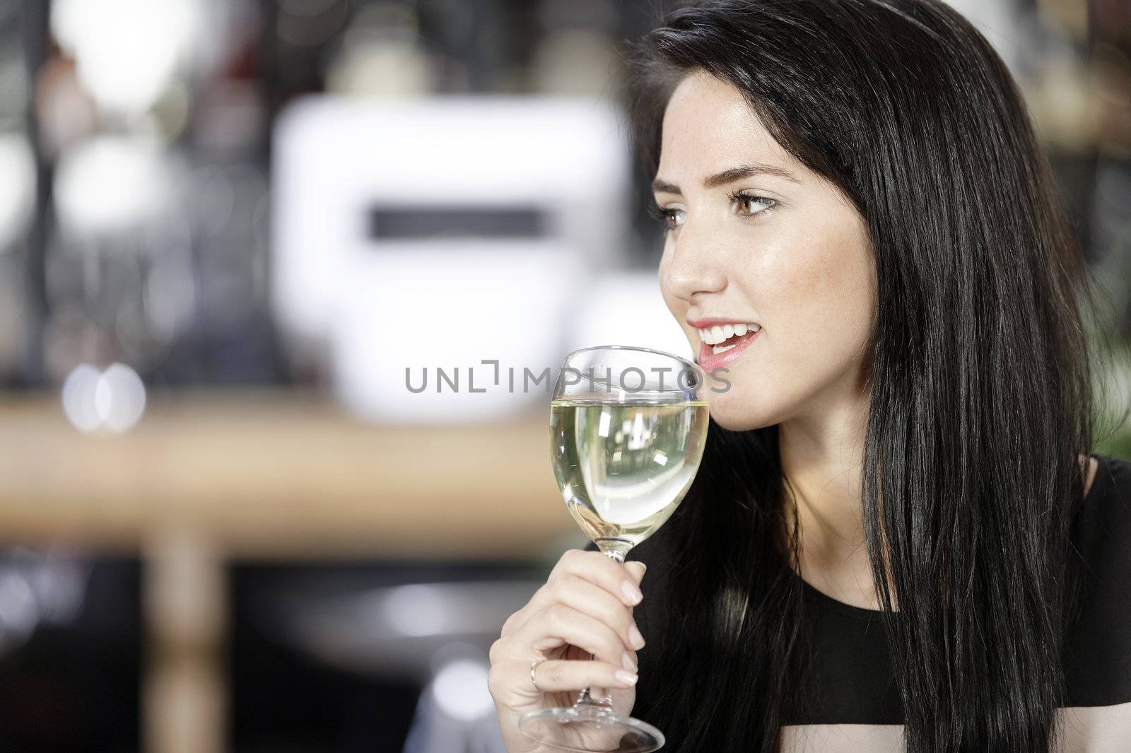 Attractive young woman enjoying a glass of white wine in a wine bar.