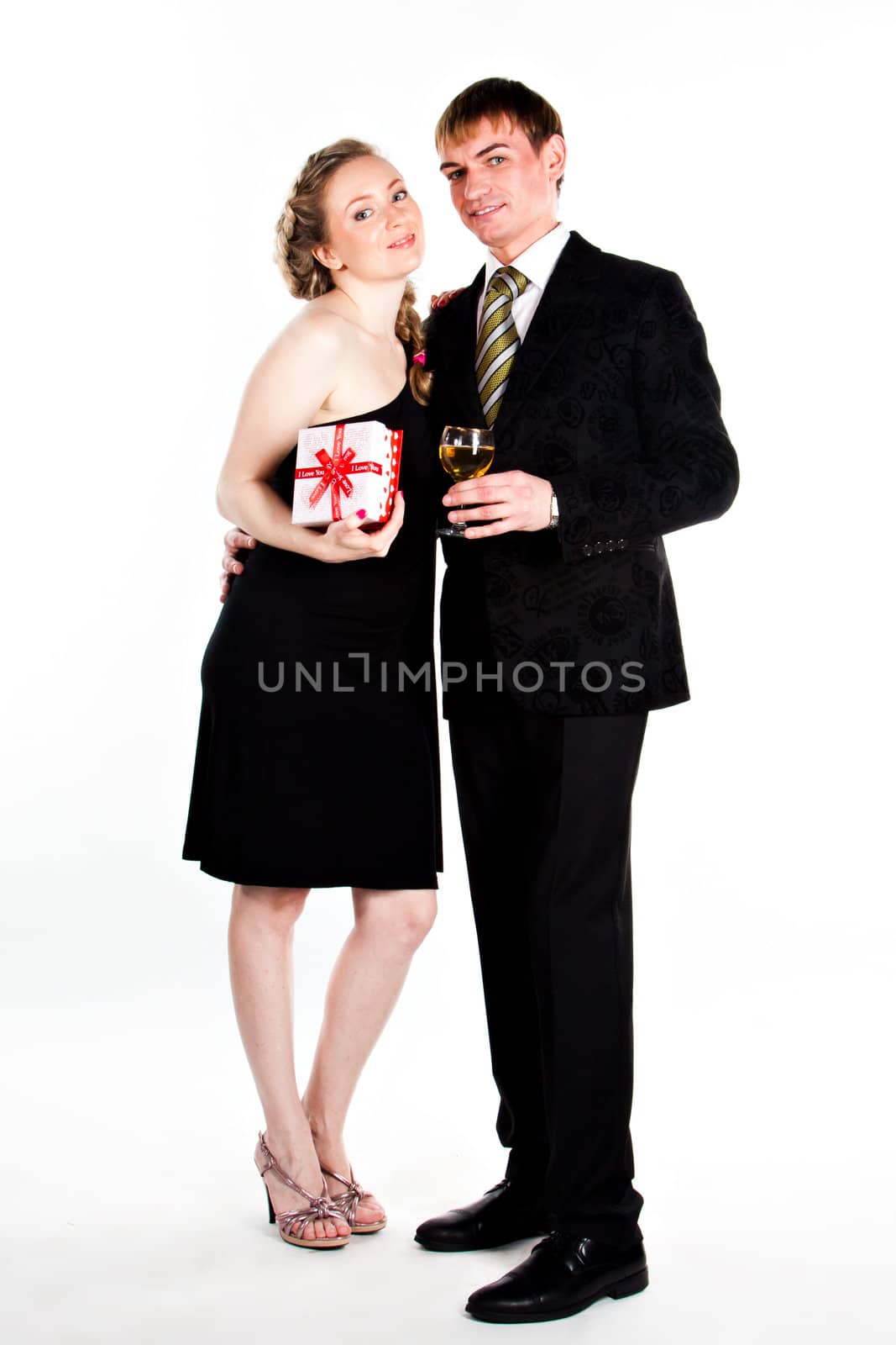 Portrait of a beautiful young couple with glasses of wine and a gift box with a red bow