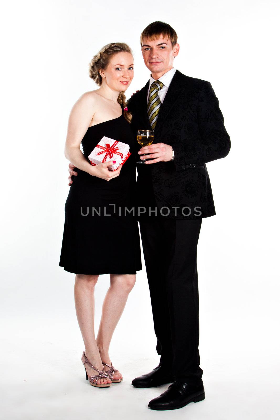 Portrait of a beautiful young couple with glasses of wine and a gift box with a red bow