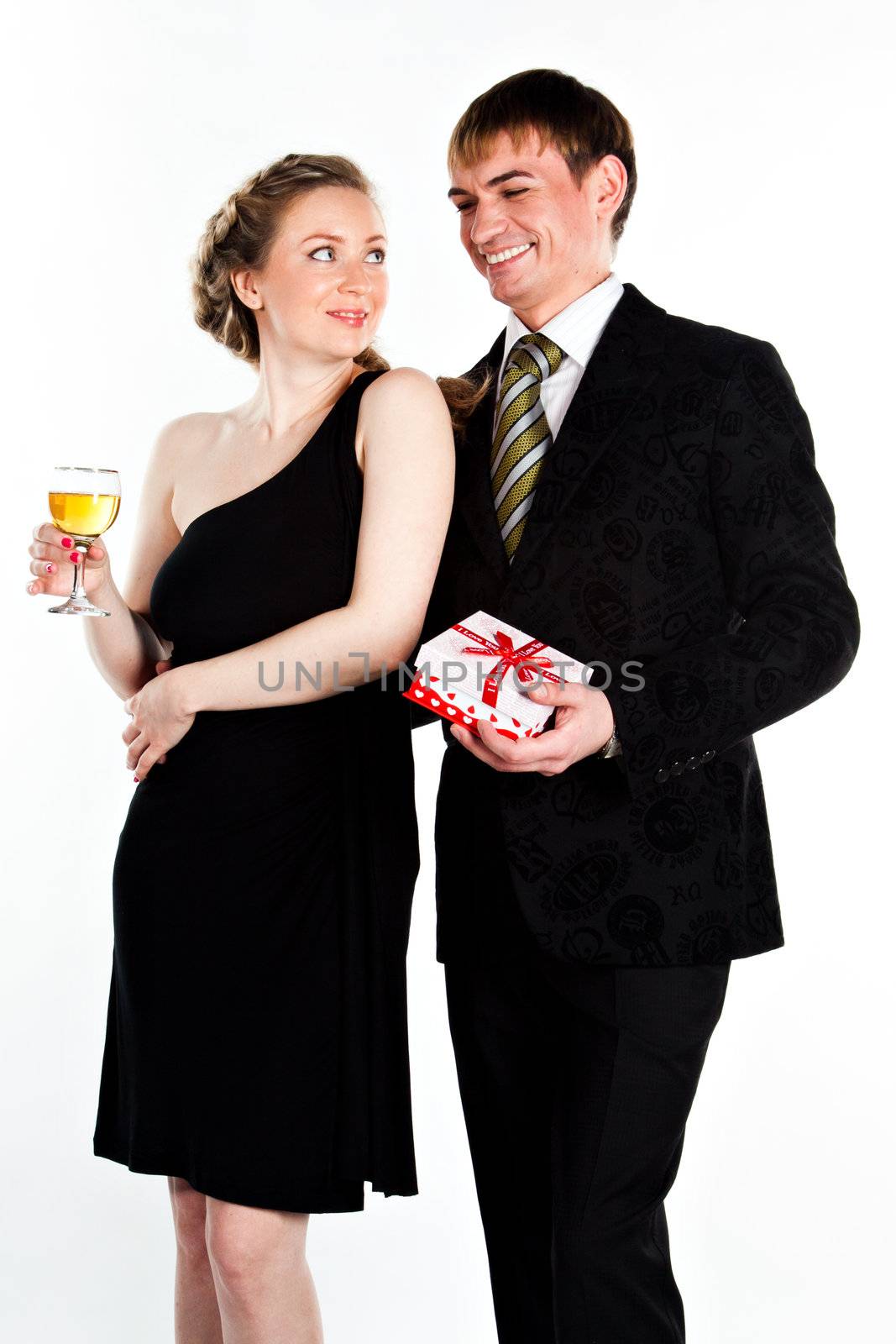 Portrait of a beautiful young couple with glasses of wine and a gift box with a red bow