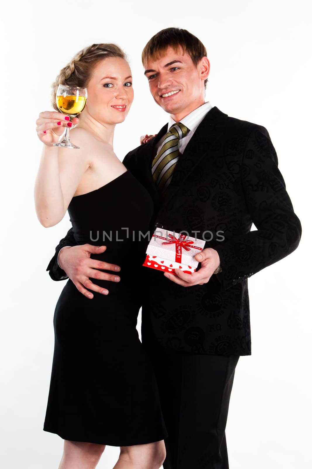Portrait of a beautiful young couple with glasses of wine and a gift box with a red bow