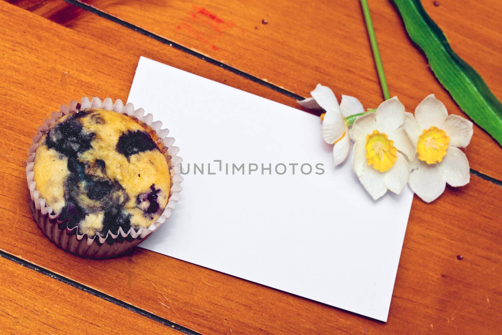 Cupcake with a note and a flower on the table 