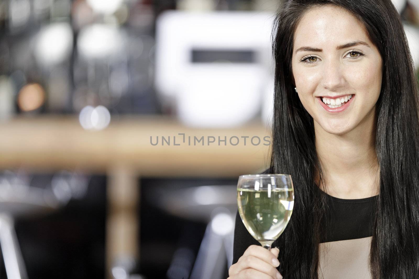 Attractive young woman enjoying a glass of white wine in a wine bar.