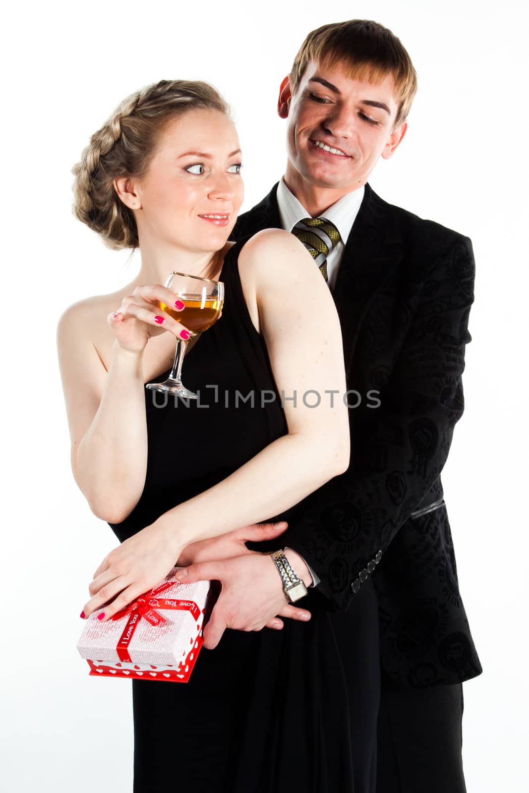 Portrait of a beautiful young couple with glasses of wine and a gift box with a red bow
