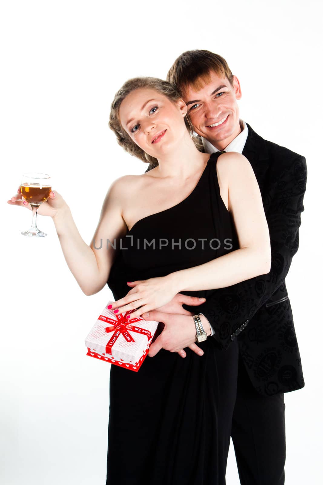 Portrait of a beautiful young couple with glasses of wine and a gift box with a red bow