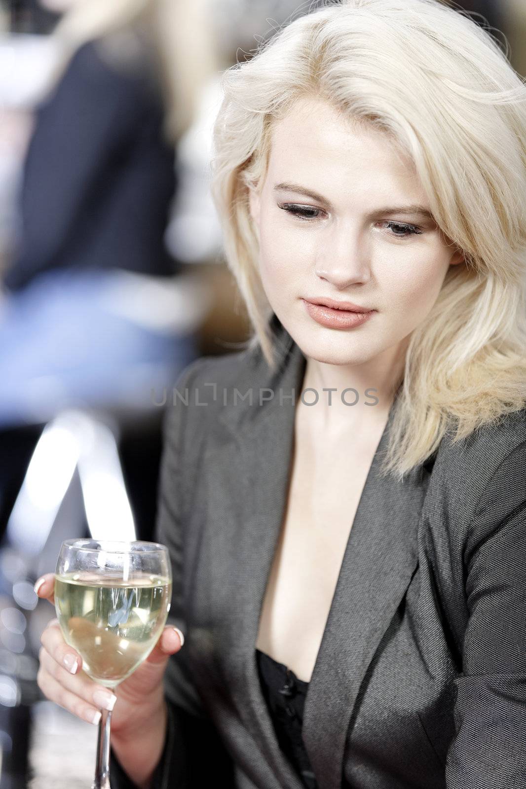 Attractive young woman enjoying a glass of white wine in a wine bar.