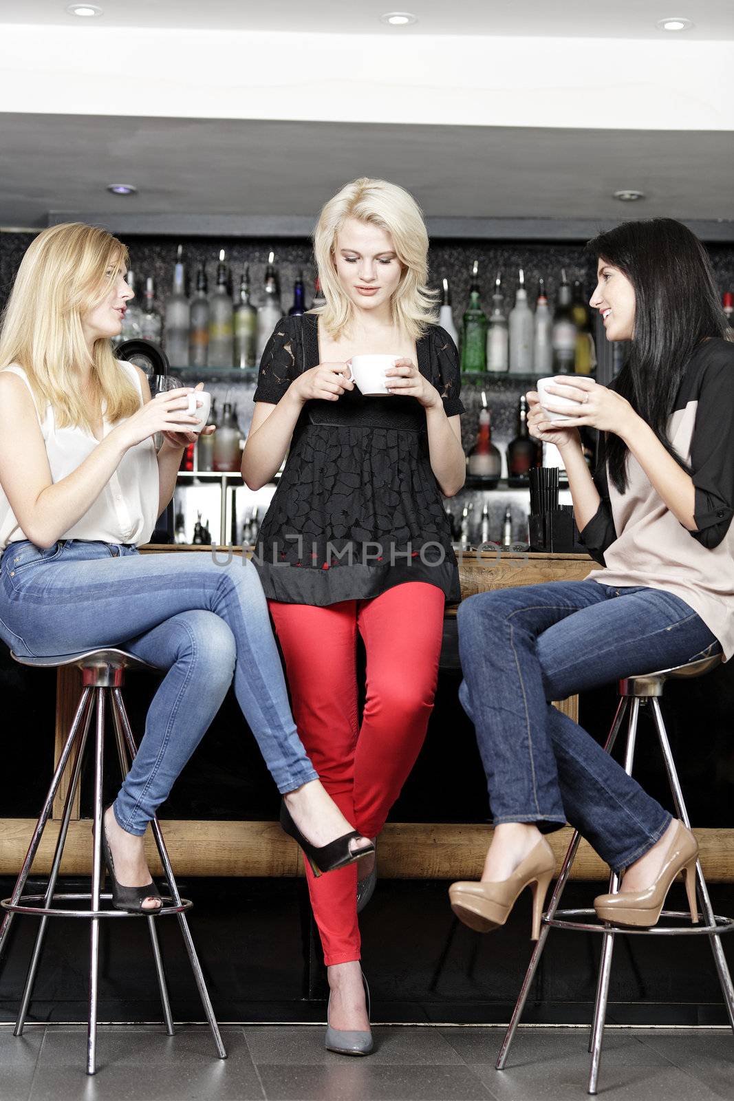 Women chatting over coffee at wine bar by studiofi