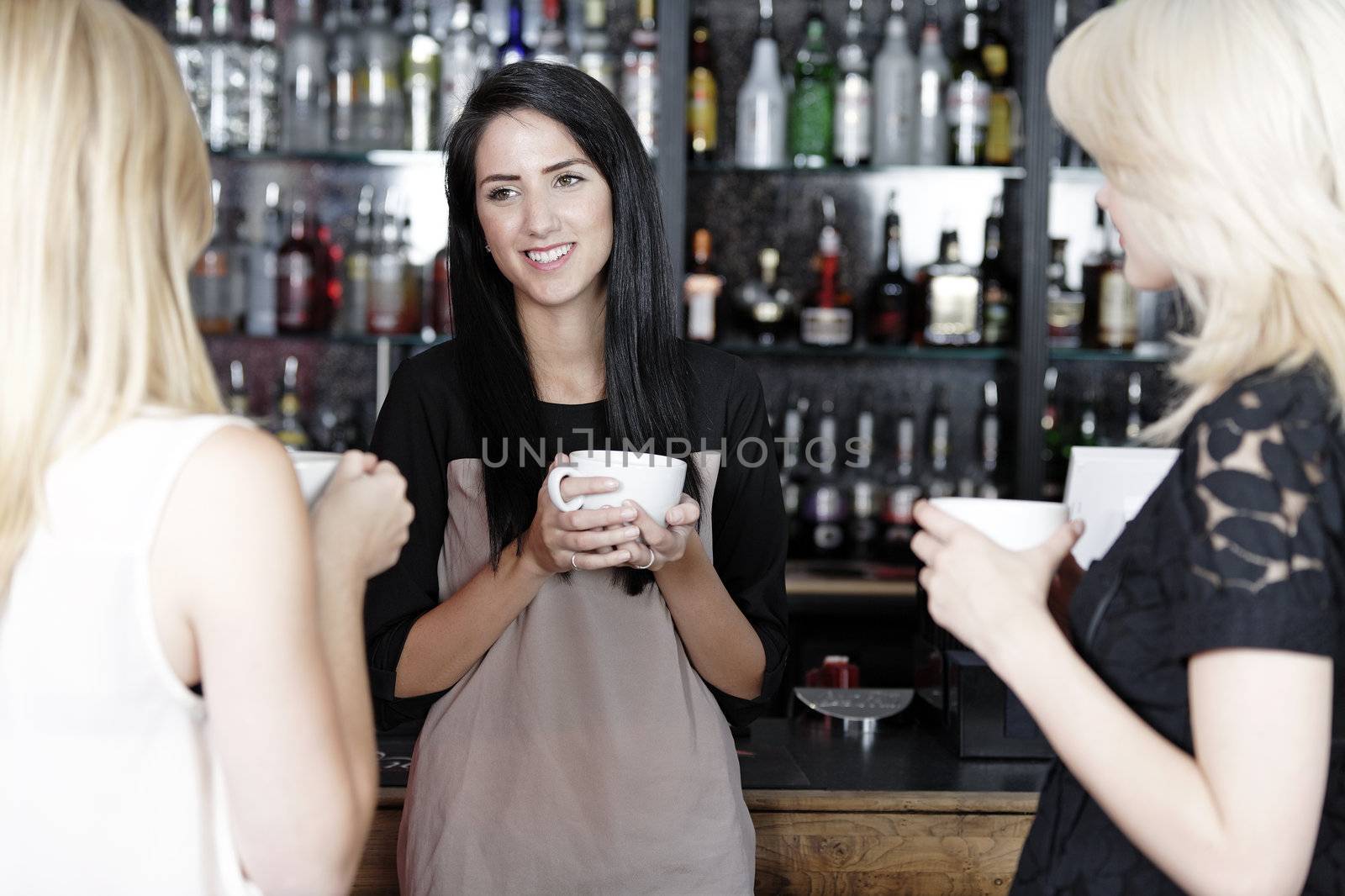 Women chatting over coffee at wine bar by studiofi