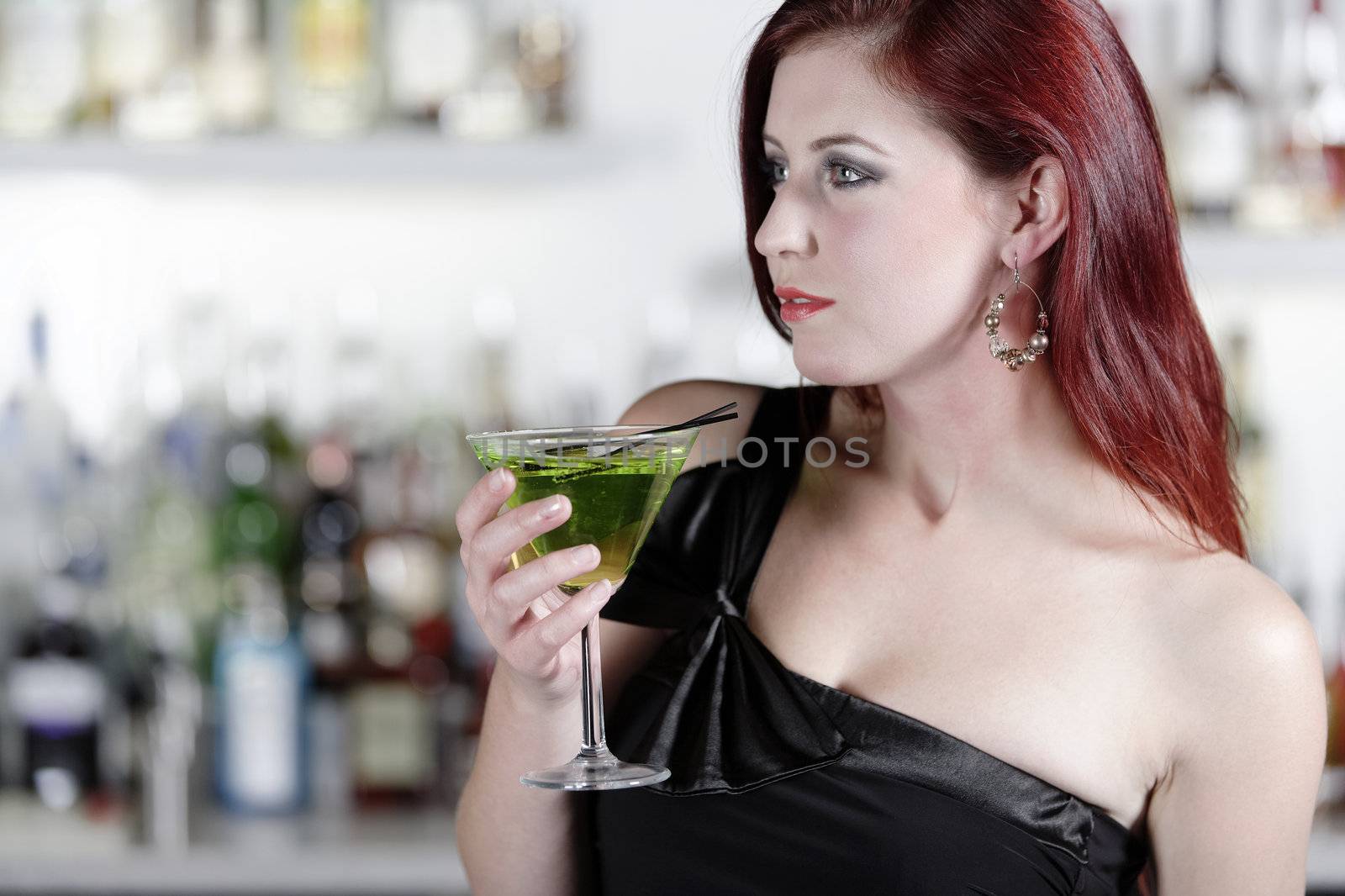 Beautiful young woman enjoying a cocktail drink at a bar
