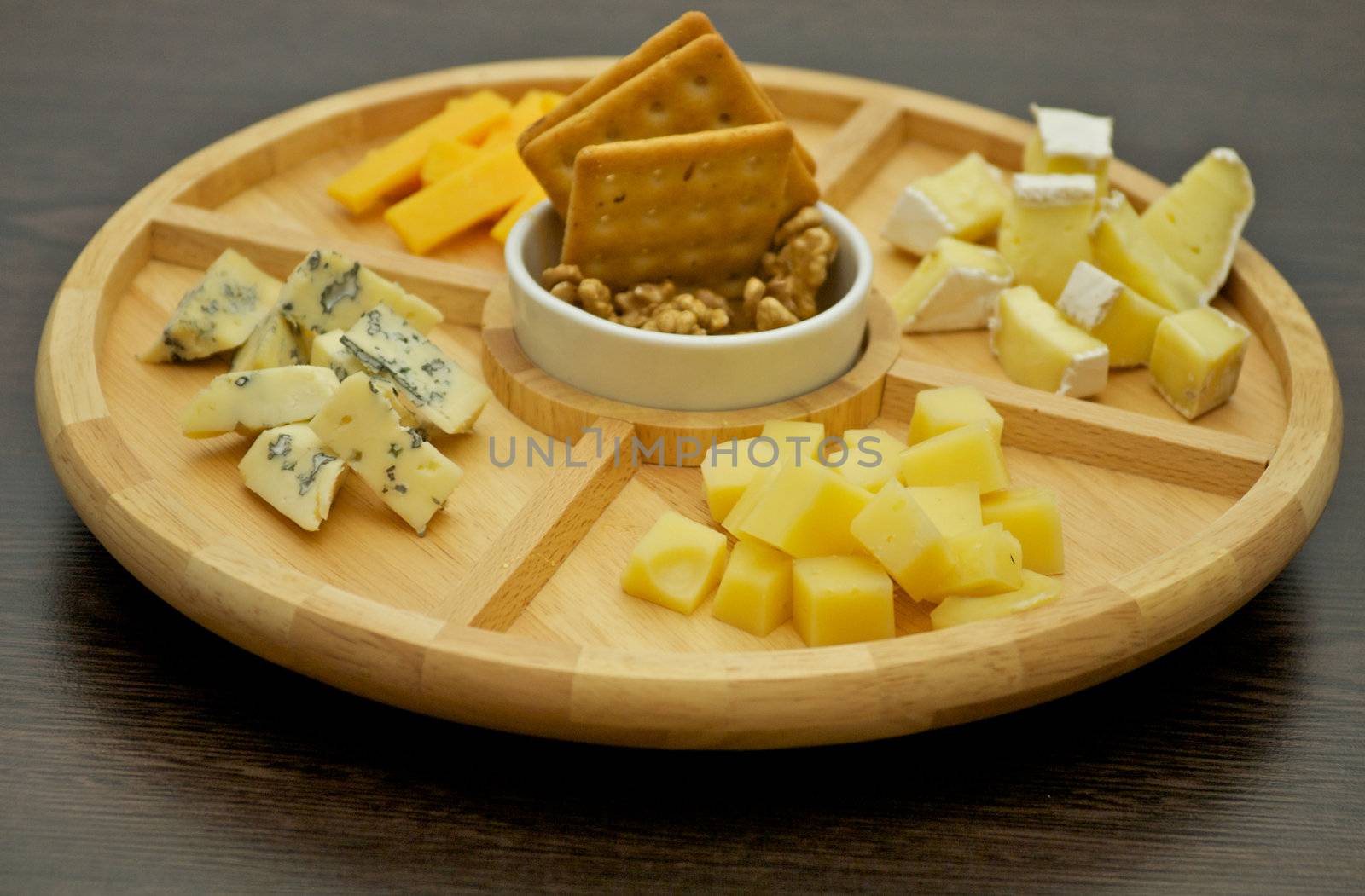 Various types of cheese on wooden plate