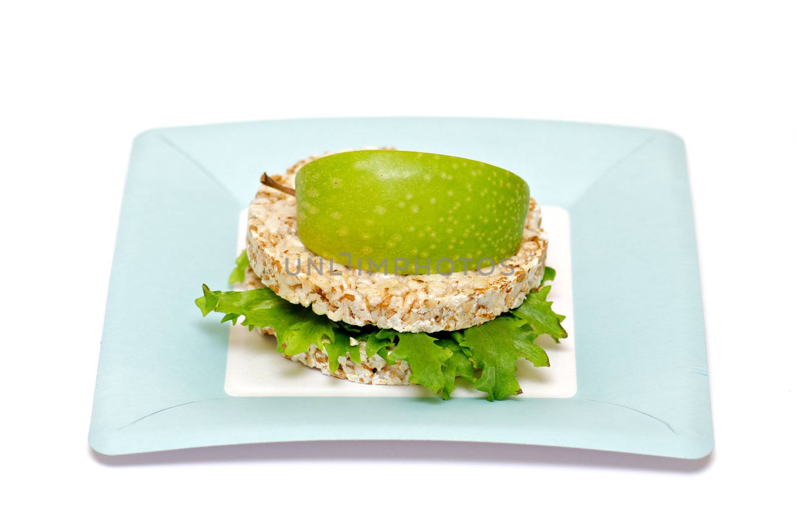 Gramineae Crispbread with Salad leaves and apple isolated on blue plate