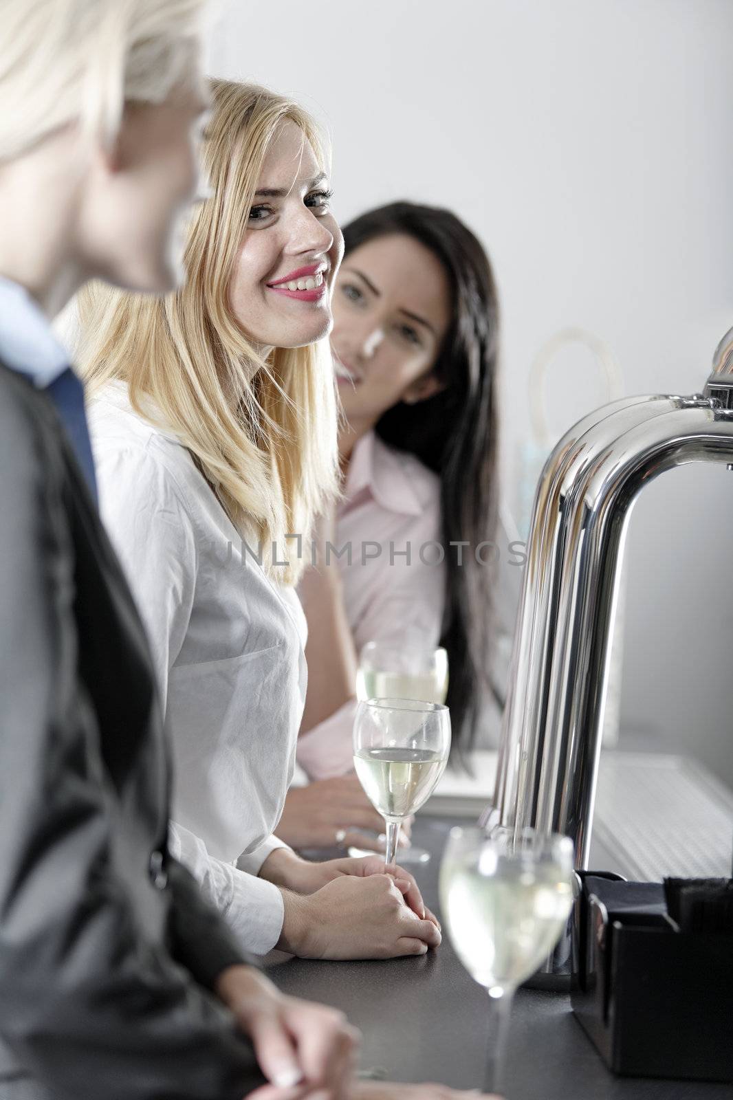 Beautiful young women enjoying a glass of wine after work at a bar.