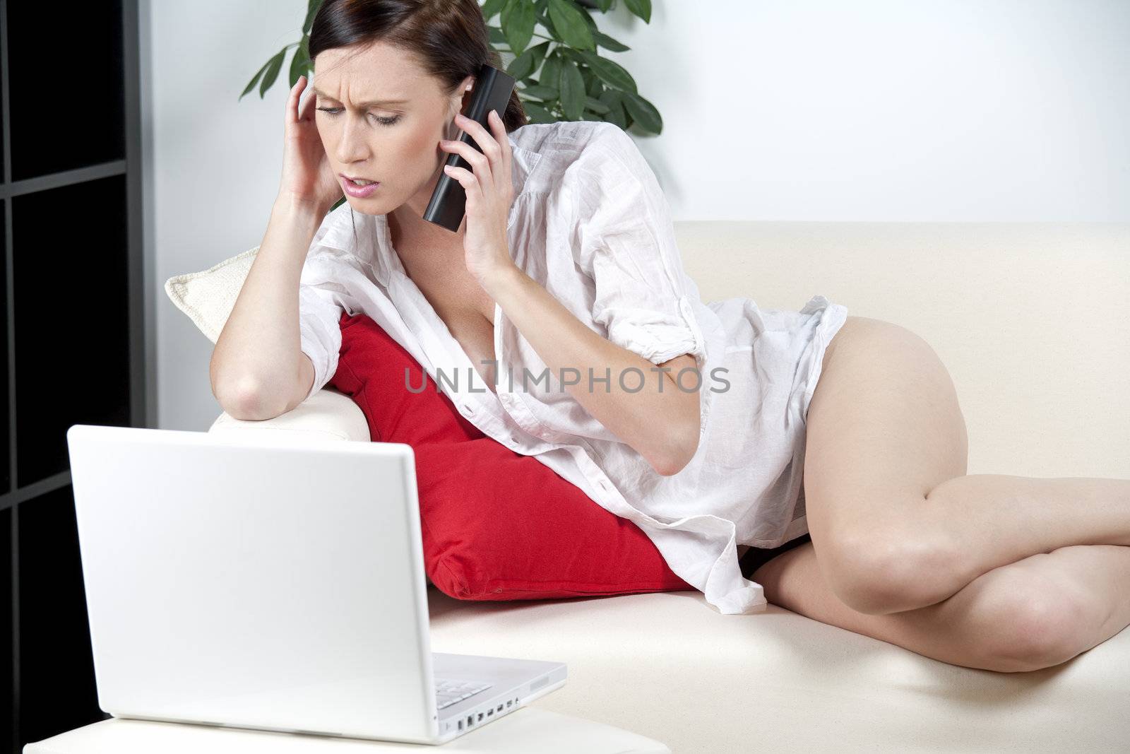 Young woman on sofa using laptop and phone