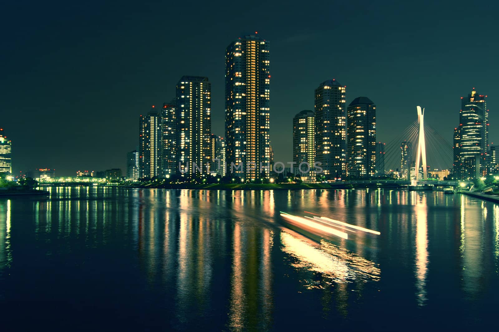 modern Tokyo buildings with night reflection in water and light traces of moving ship, Japan