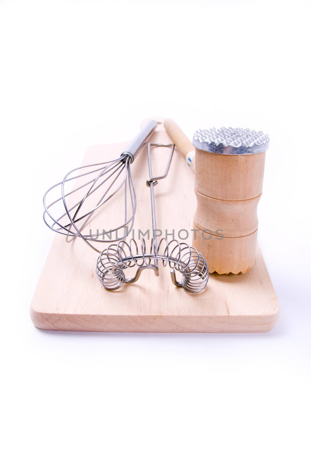 Kitchen utensil set. Meat tenderizer with egg whisks lying on kitchen board. Isolated on white.