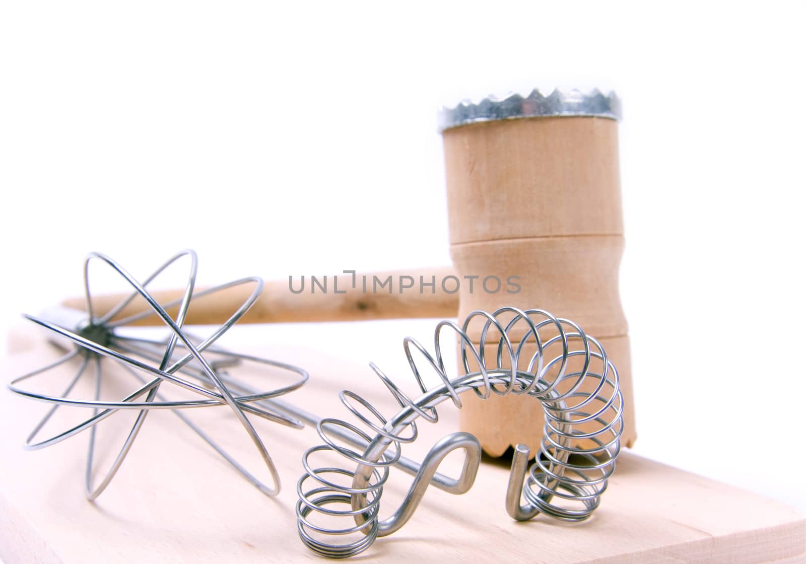 Kitchen utensil set. Meat tenderizer with egg whisks lying on kitchen board. Isolated on white.