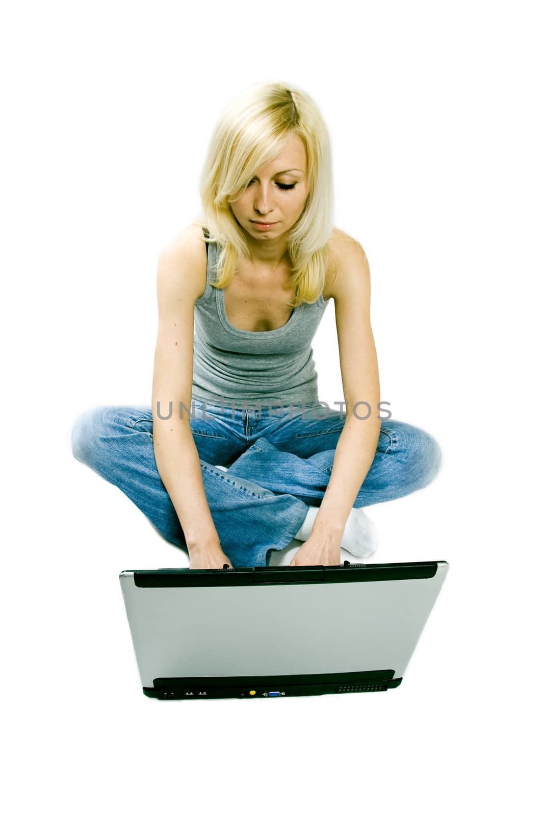 A studio shoot of a beautiful young girl sitting with a computer on the floor and writing