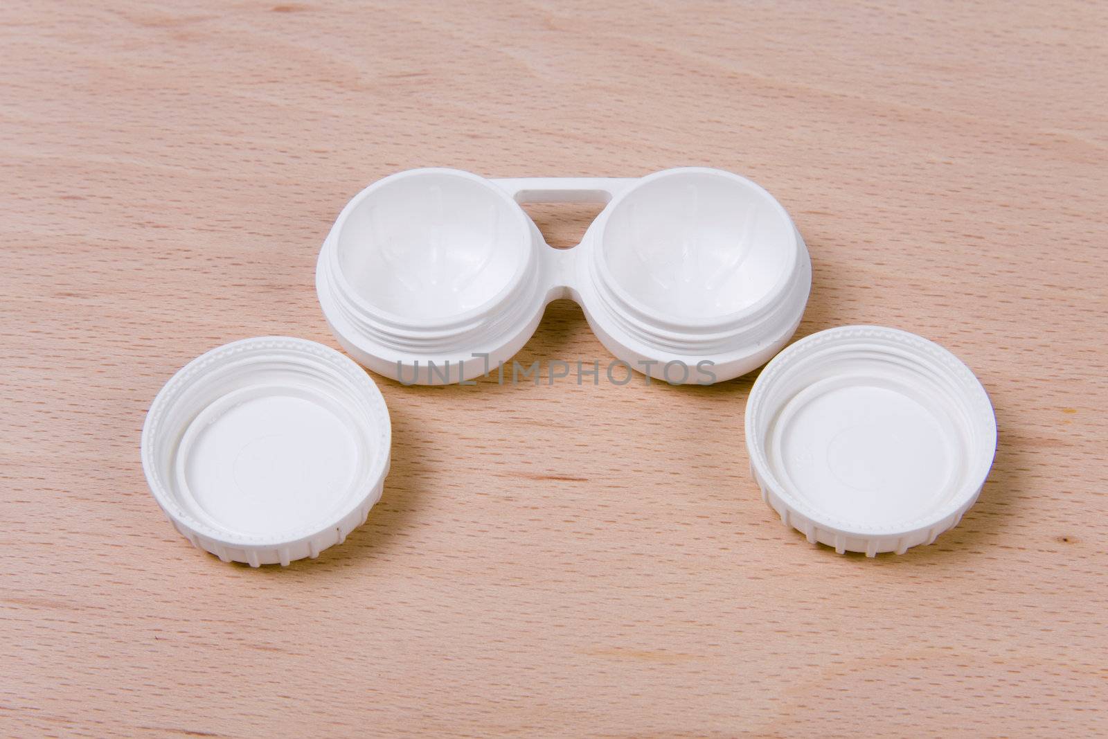 Set of compact lens case. On wooden background.