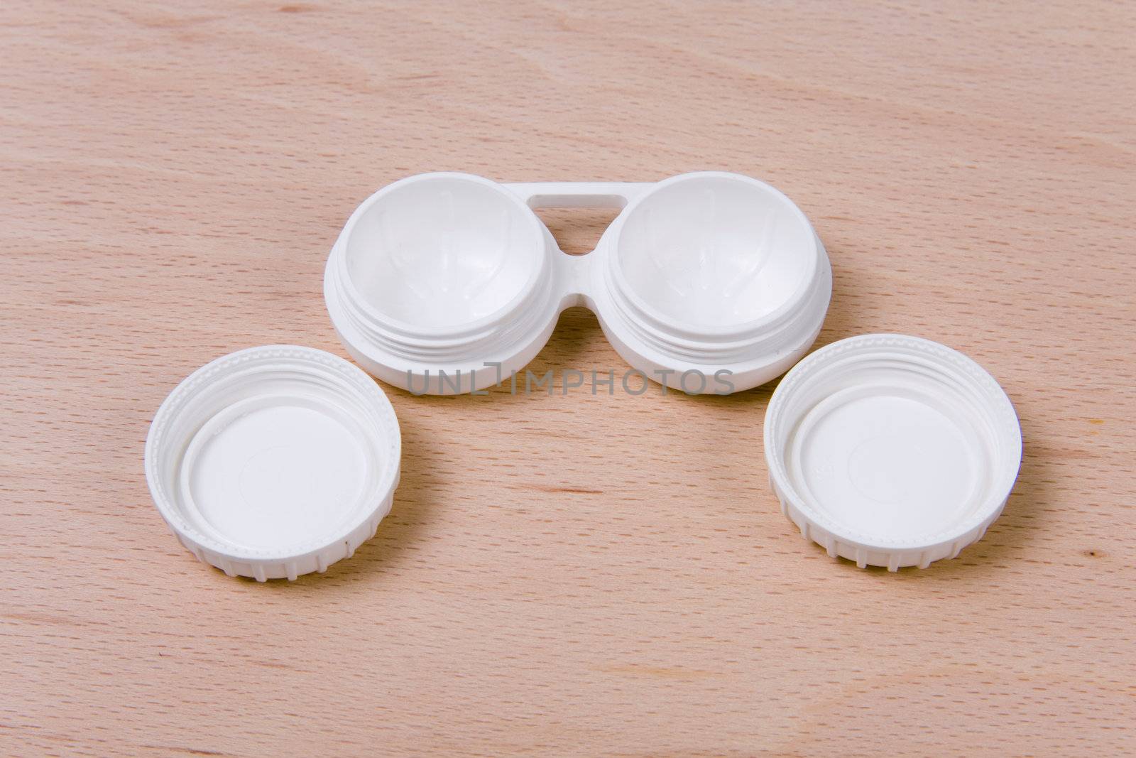 Set of compact lens case. On wooden background.