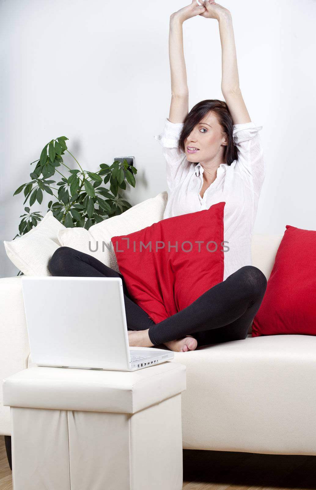 Woman stretching on a sofa with laptop