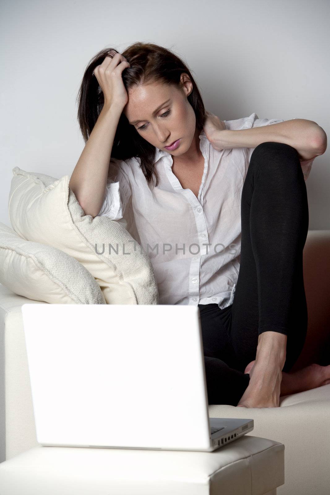 Woman sat on sofa with laptop expressing concern